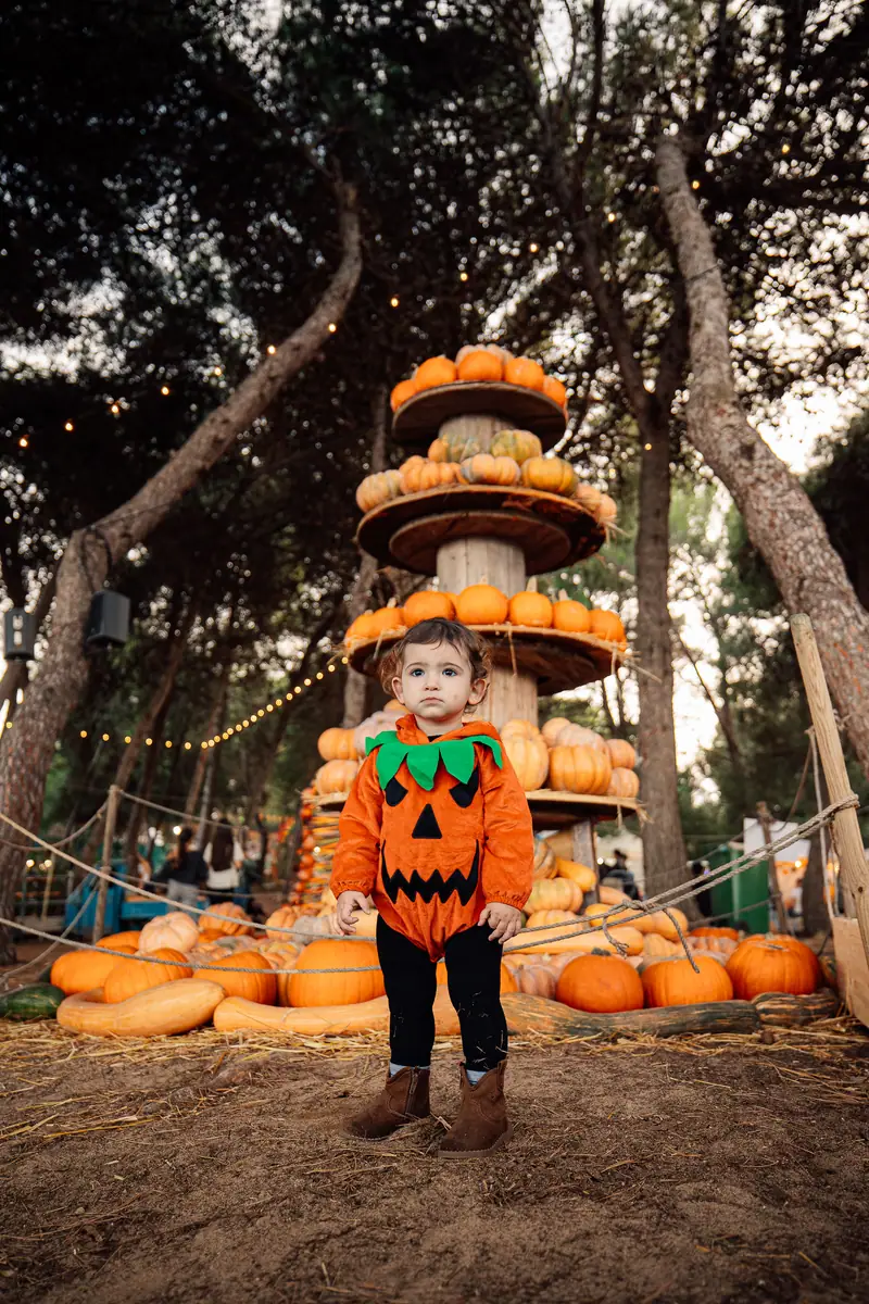 Bimbo costume zucca davanti torre zucche