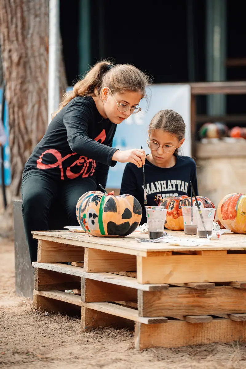 Due ragazze dipingono zucca su pallet